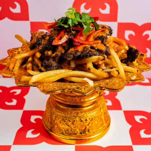Ban Ban Burger's loaded fries with beef, sauce, red peppers, and cilantro on a golden pedestal.